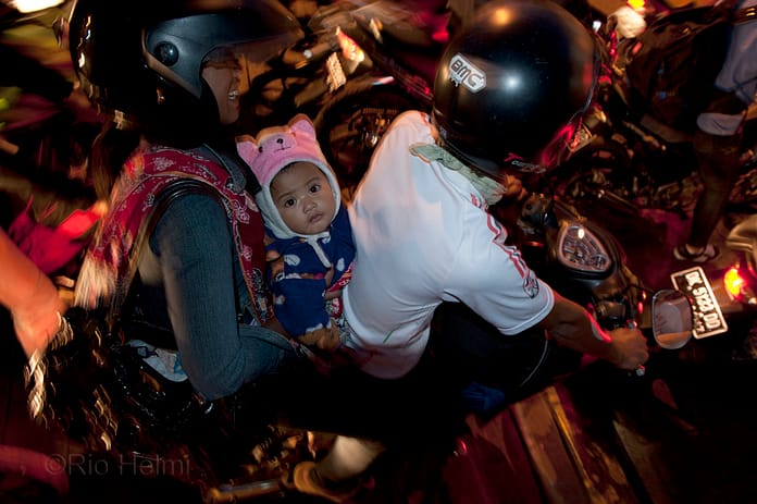 A batch of motorcyclists, migrant workers heading home to Java for Idul Fitri end-of-Ramadan holidays, rush to get a spot on their designated ferry at the Gilimanuk crossing in Bali. Amid the rush children are held tightly by their parents. Some families like these will travel up to 10 hours by motorcycle.